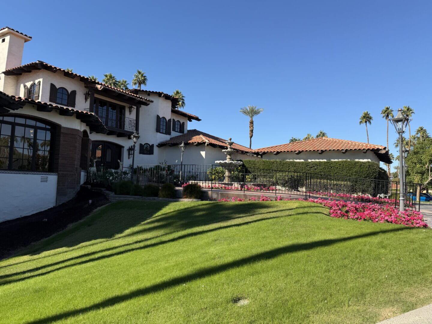 Sunny day at a charming courtyard with green lawns and palm trees.