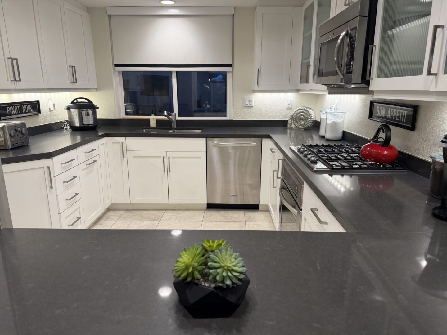 Modern kitchen with white cabinets and black countertops.