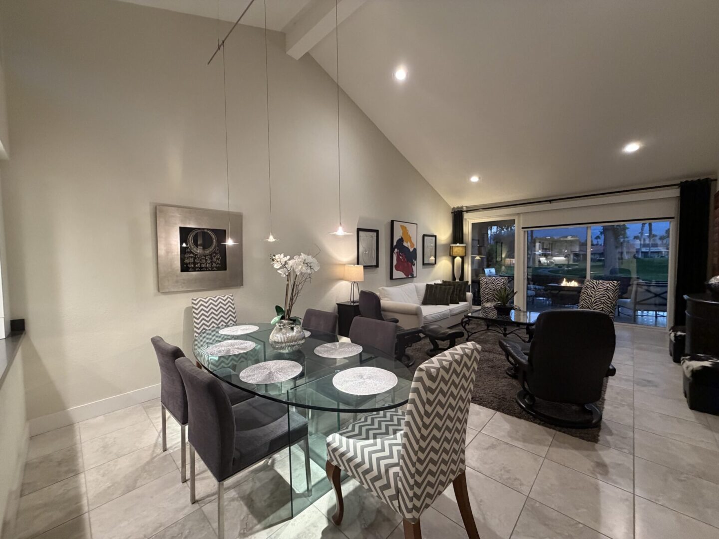 Modern dining room with glass table and stylish chairs under pendant lights.