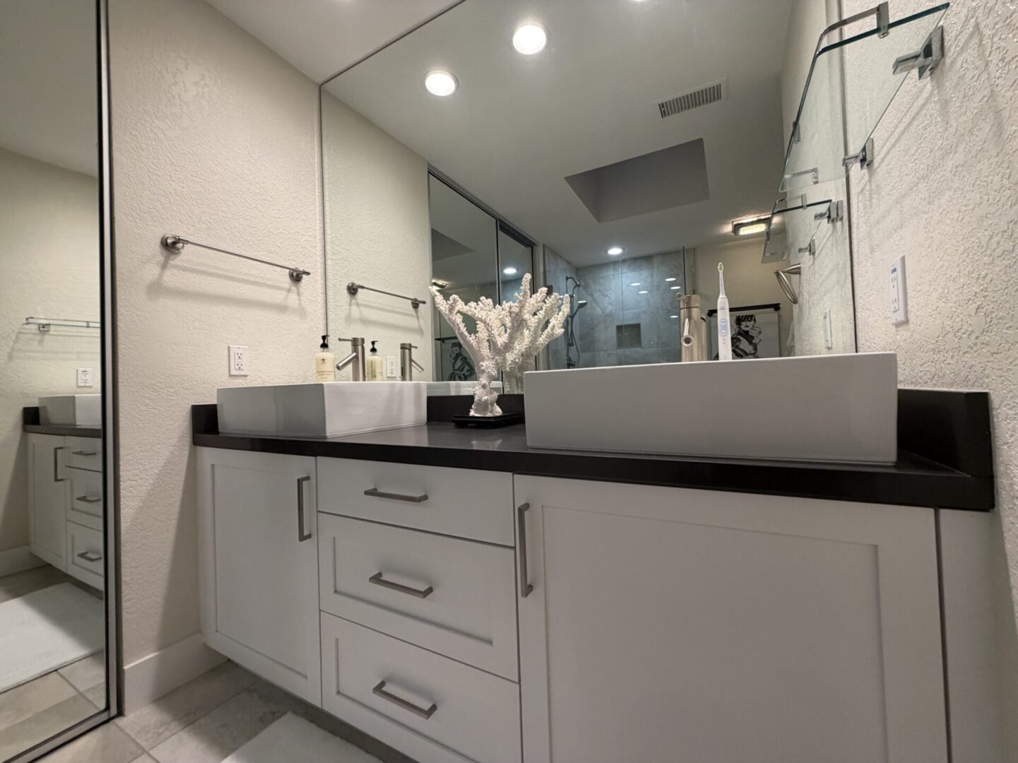 Modern white bathroom vanity with large mirror and decorative centerpiece.