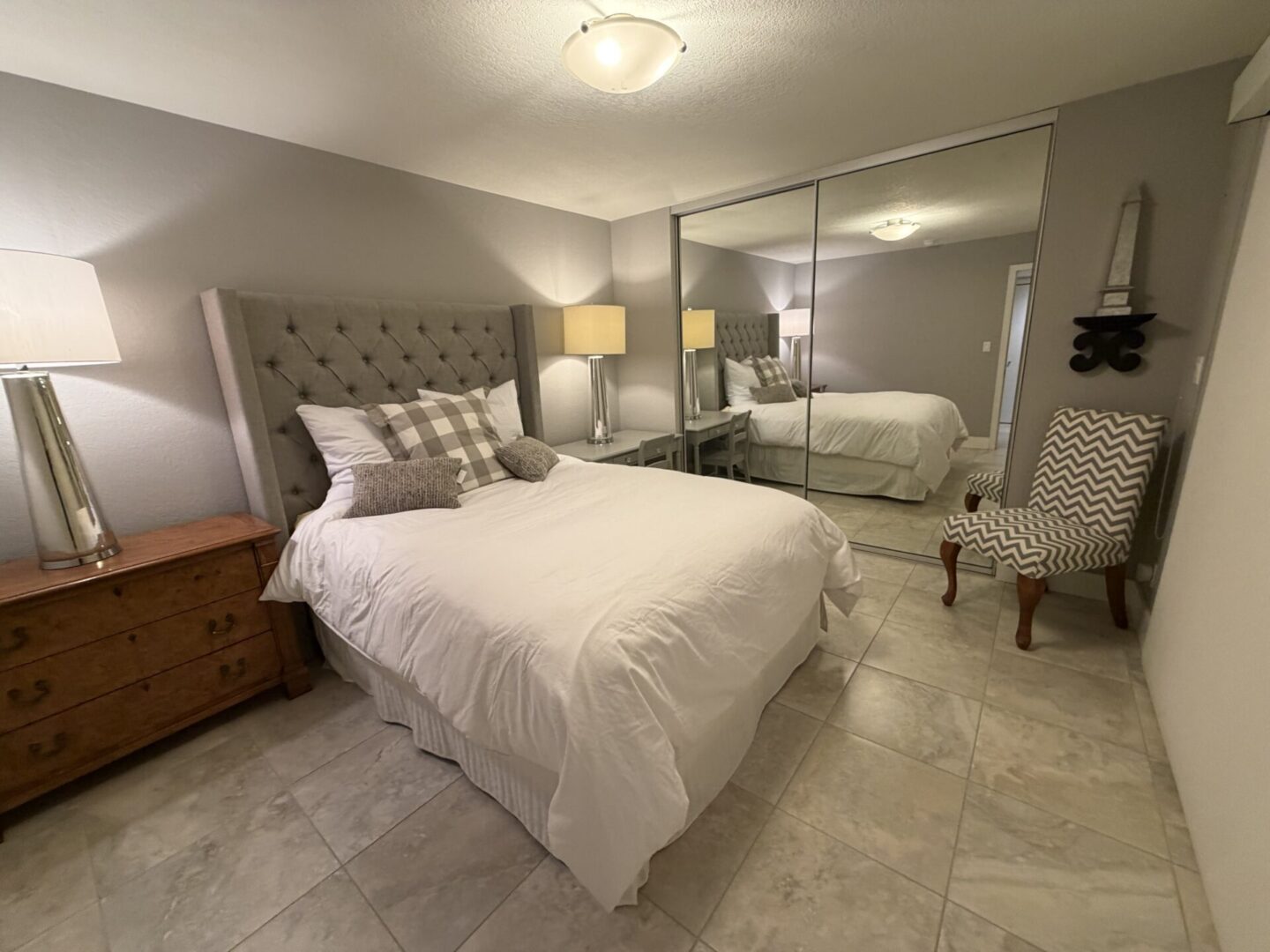 Cozy bedroom with tufted headboard and mirrored closet doors.