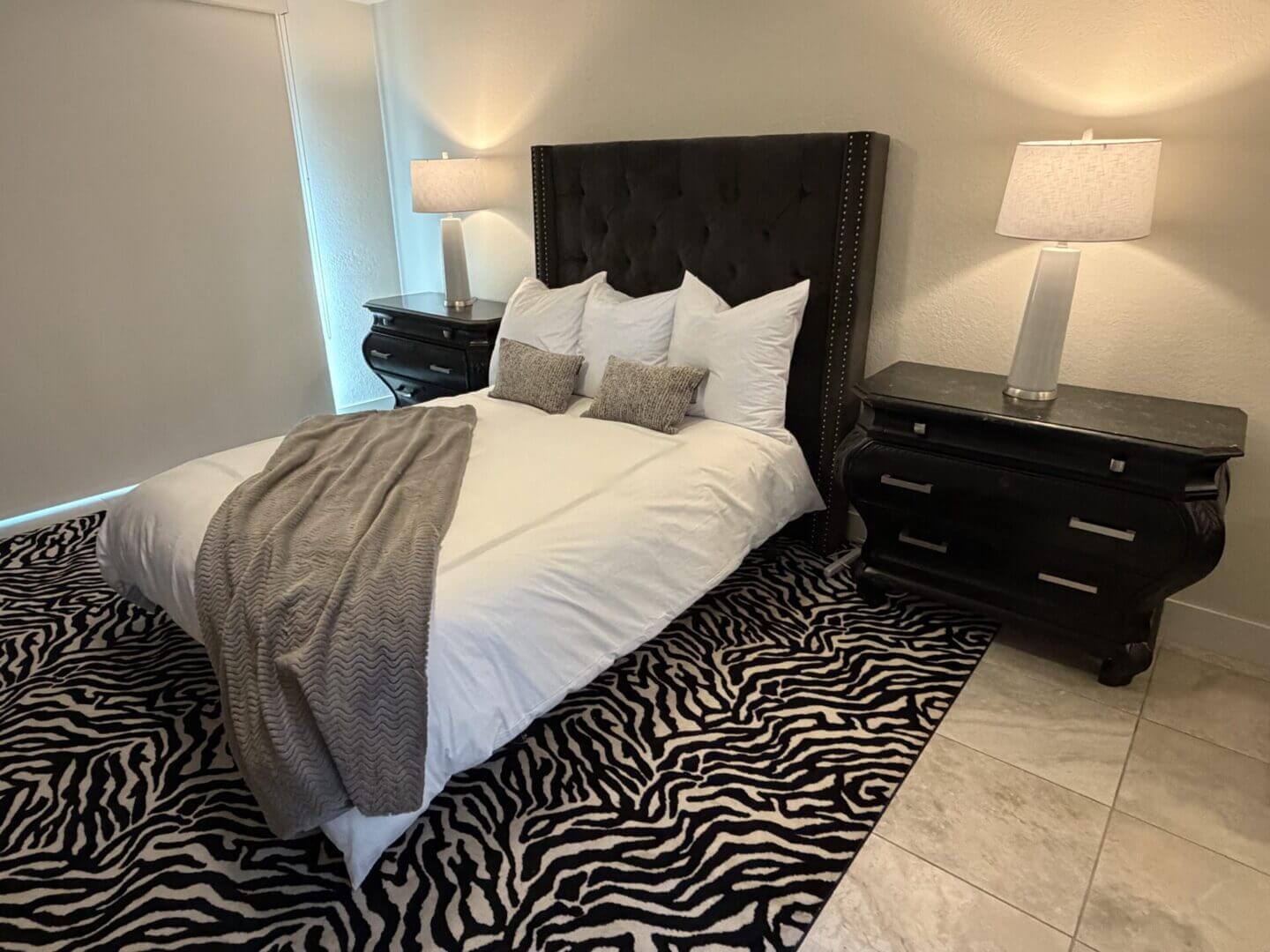 Modern bedroom with zebra print rug and elegant black furniture.