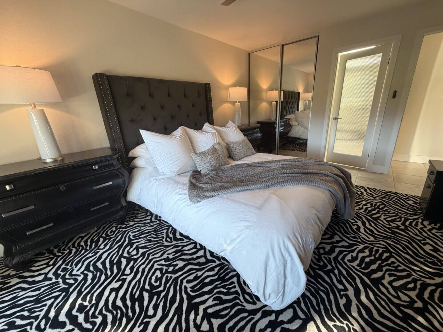 Cozy bedroom with a tufted headboard and zebra print rug.